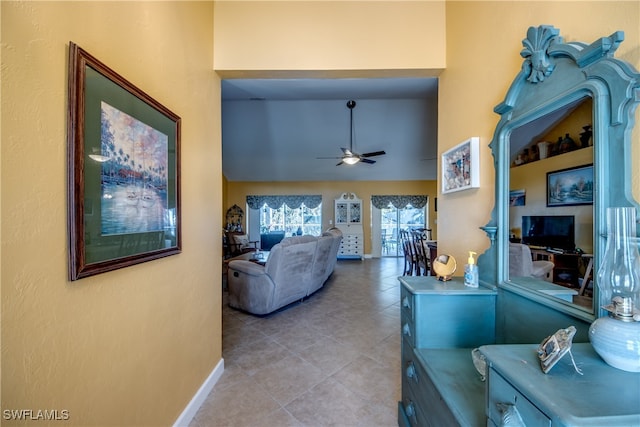 living room with ceiling fan, a towering ceiling, and light tile patterned floors