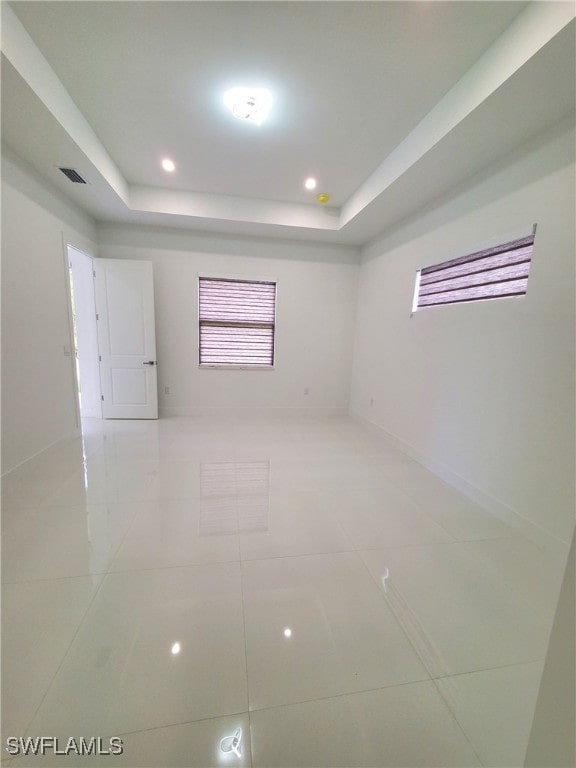 tiled spare room featuring a raised ceiling