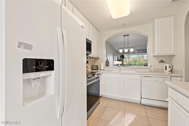 kitchen featuring sink, hanging light fixtures, white cabinets, light tile patterned flooring, and appliances with stainless steel finishes