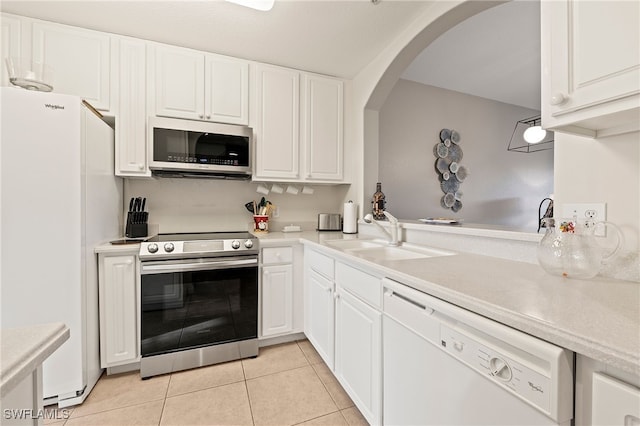 kitchen with light tile patterned flooring, light countertops, a sink, appliances with stainless steel finishes, and arched walkways