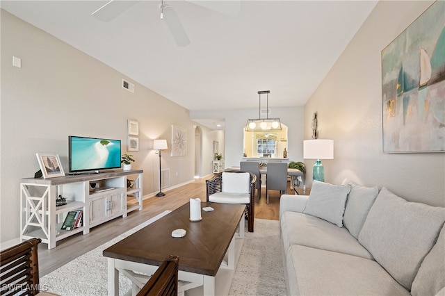 living room featuring a ceiling fan, visible vents, baseboards, and wood finished floors