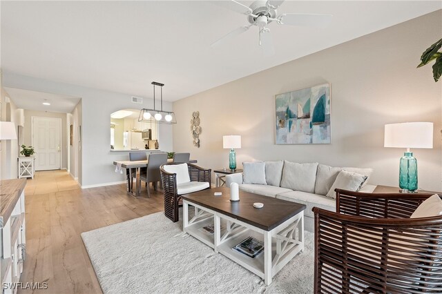 living room featuring a ceiling fan, light wood-style flooring, baseboards, and visible vents
