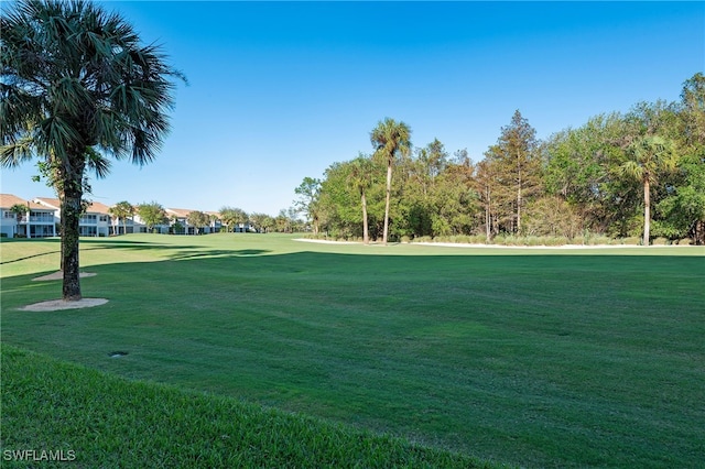 view of home's community with view of golf course and a lawn