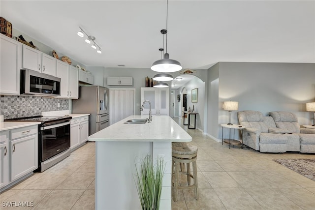 kitchen featuring sink, backsplash, pendant lighting, a center island with sink, and appliances with stainless steel finishes