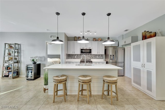 kitchen with sink, white cabinets, hanging light fixtures, and appliances with stainless steel finishes