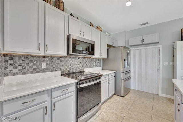 kitchen featuring white cabinetry, stainless steel appliances, light tile patterned floors, and tasteful backsplash