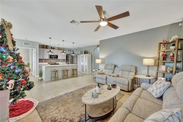 tiled living room featuring ceiling fan and sink