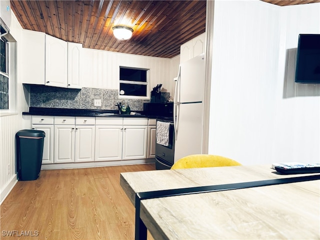 kitchen with white cabinetry, white fridge, light hardwood / wood-style floors, and stainless steel range oven