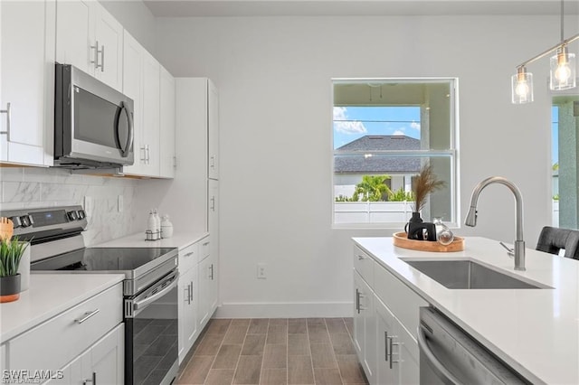 kitchen with hanging light fixtures, white cabinetry, sink, and appliances with stainless steel finishes