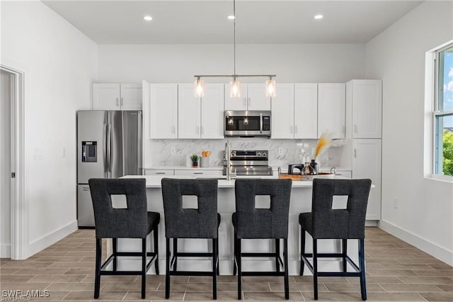 kitchen featuring a healthy amount of sunlight, an island with sink, and appliances with stainless steel finishes