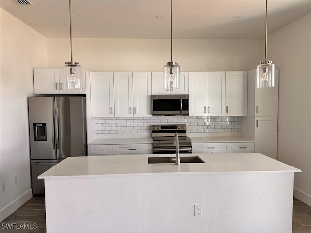 kitchen featuring white cabinets, pendant lighting, a center island with sink, and appliances with stainless steel finishes