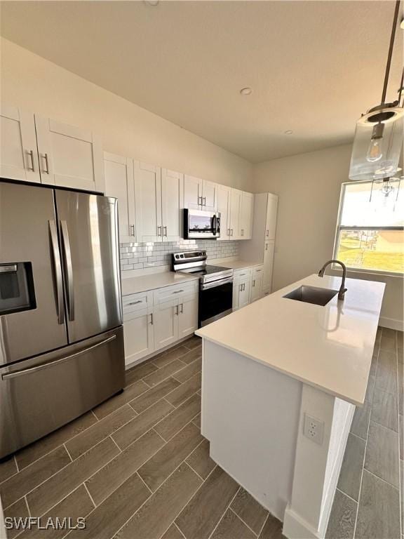 kitchen featuring white cabinets, sink, stainless steel appliances, and hanging light fixtures