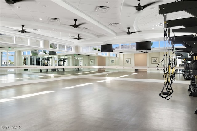 gym with a towering ceiling, a paneled ceiling, and ceiling fan