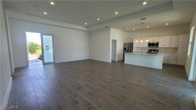 kitchen featuring white cabinets, dark hardwood / wood-style flooring, stainless steel appliances, and an island with sink