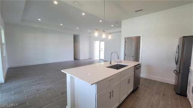 kitchen with white cabinetry, a kitchen island with sink, sink, and appliances with stainless steel finishes