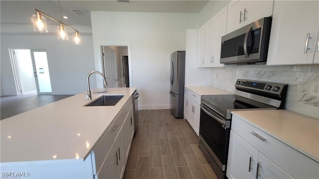 kitchen with appliances with stainless steel finishes, dark wood-type flooring, sink, decorative light fixtures, and white cabinets