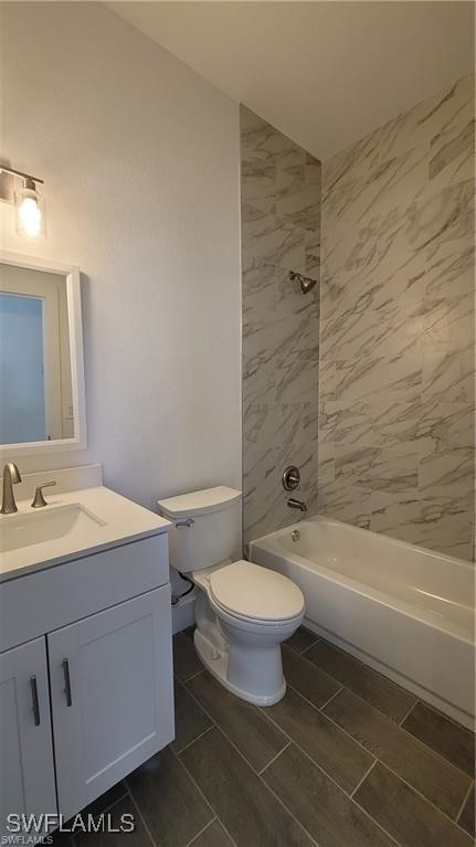 full bathroom with vanity, tiled shower / bath combo, and toilet