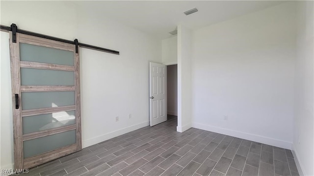 unfurnished room with a barn door and dark wood-type flooring