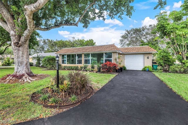 ranch-style house featuring aphalt driveway, a front yard, brick siding, and an attached garage