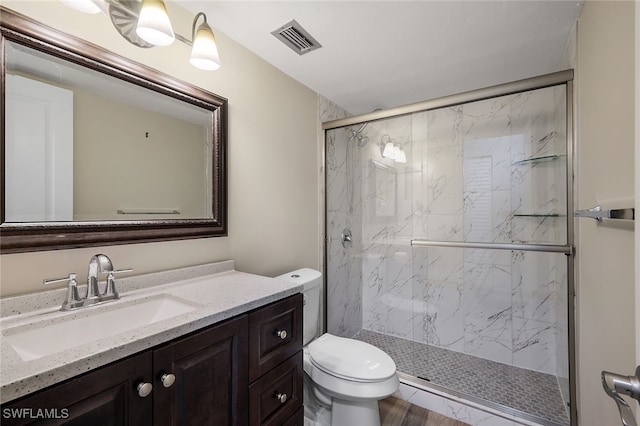 bathroom featuring toilet, vanity, a marble finish shower, and visible vents