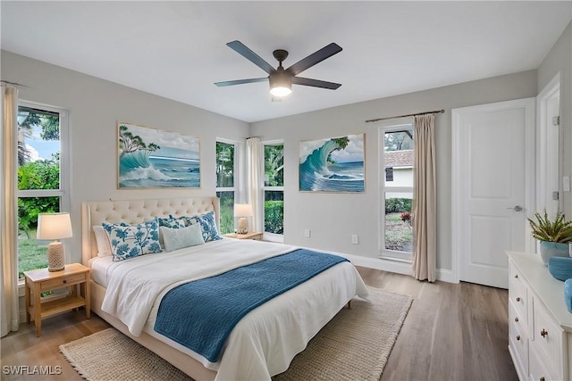 bedroom featuring multiple windows, light hardwood / wood-style floors, and ceiling fan