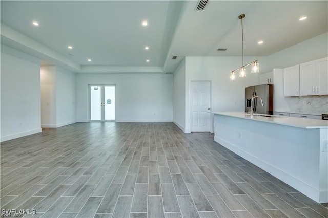 kitchen featuring pendant lighting, white cabinets, light hardwood / wood-style floors, and sink