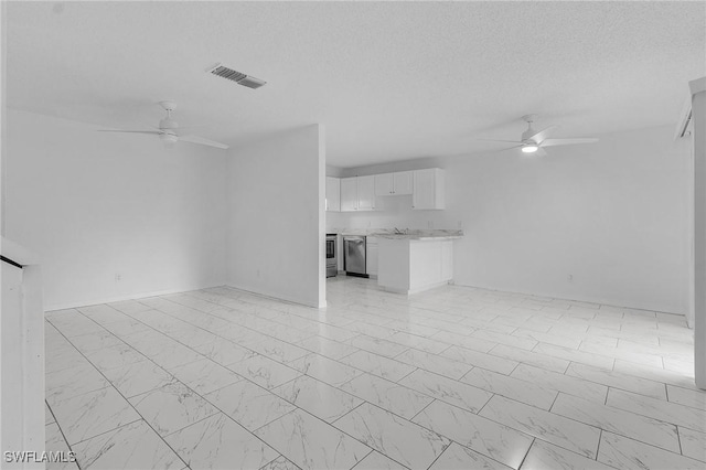 unfurnished living room featuring ceiling fan and a textured ceiling