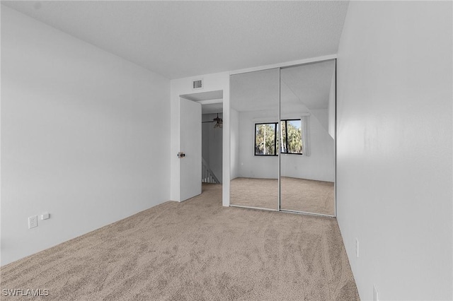 unfurnished bedroom with light carpet and a closet