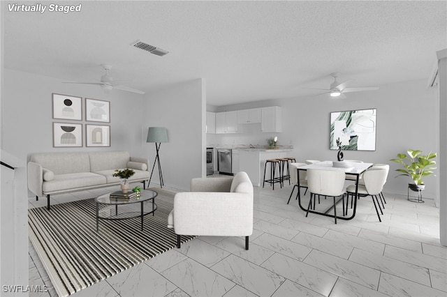 living room featuring ceiling fan and a textured ceiling