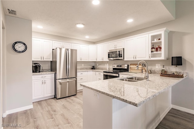 kitchen featuring kitchen peninsula, white cabinetry, sink, and appliances with stainless steel finishes