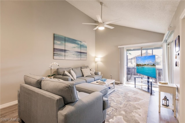 living room with ceiling fan, high vaulted ceiling, light hardwood / wood-style floors, and a textured ceiling