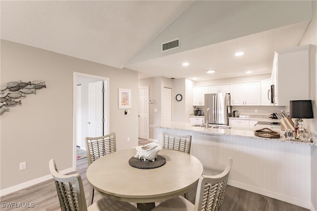 dining room with sink, hardwood / wood-style floors, and lofted ceiling