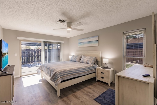 bedroom with hardwood / wood-style floors, a textured ceiling, access to outside, and ceiling fan