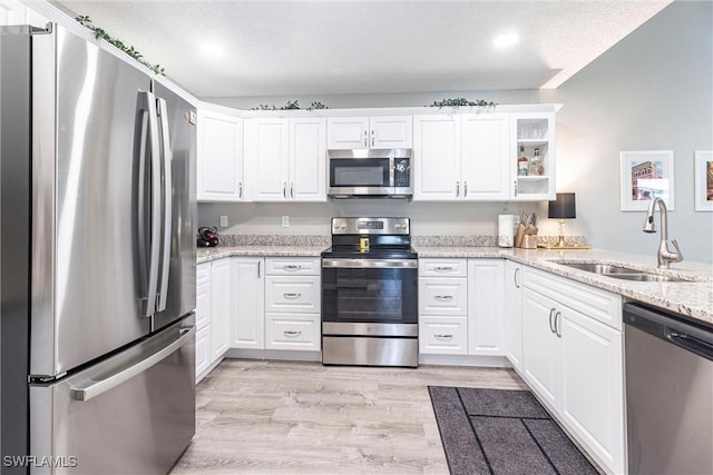 kitchen featuring a sink, appliances with stainless steel finishes, white cabinets, and light wood finished floors