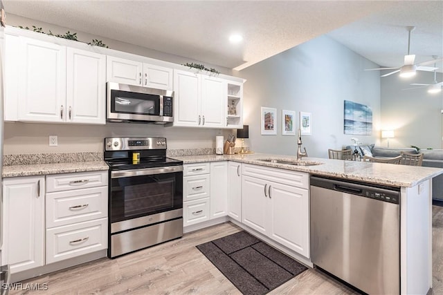 kitchen featuring a ceiling fan, a peninsula, a sink, white cabinets, and appliances with stainless steel finishes