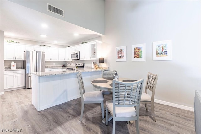 dining room with visible vents, baseboards, and light wood finished floors