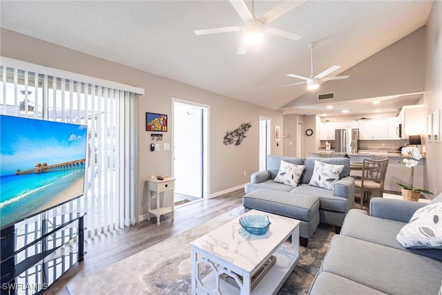 living room featuring wood finished floors, baseboards, visible vents, lofted ceiling, and ceiling fan