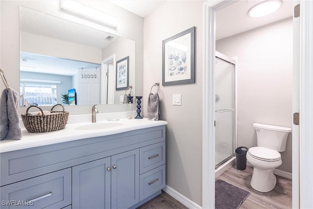 full bathroom with visible vents, toilet, a stall shower, wood finished floors, and vanity