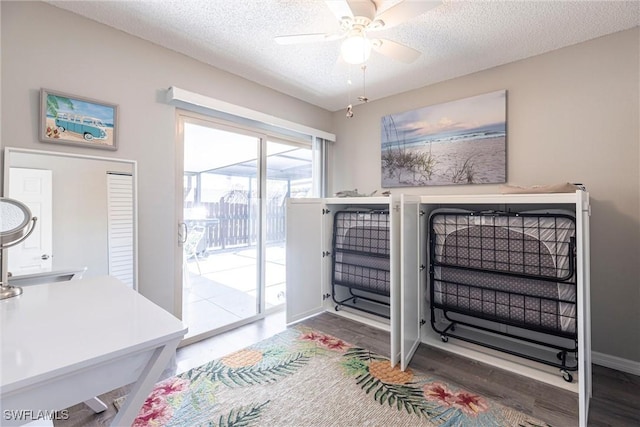 bedroom with baseboards, wood finished floors, a textured ceiling, and access to exterior