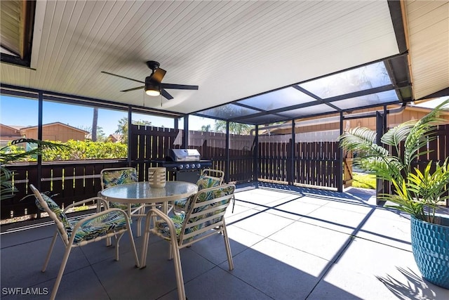 view of patio / terrace with outdoor dining space, a ceiling fan, fence, glass enclosure, and grilling area