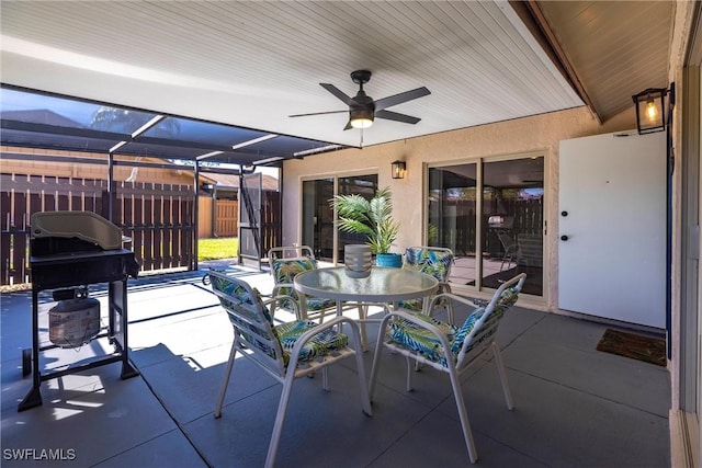 view of patio / terrace featuring area for grilling, outdoor dining space, fence, a lanai, and ceiling fan