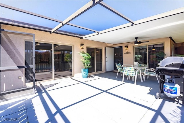 view of patio / terrace with glass enclosure, outdoor dining area, area for grilling, and ceiling fan