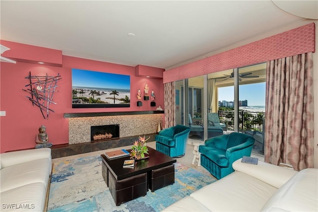 living room with a tile fireplace and ceiling fan