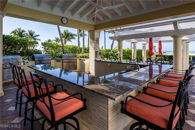 view of patio with ceiling fan, an outdoor bar, a grill, and an outdoor kitchen