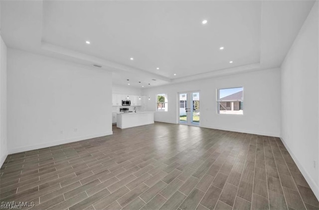 unfurnished living room featuring a raised ceiling and wood-type flooring