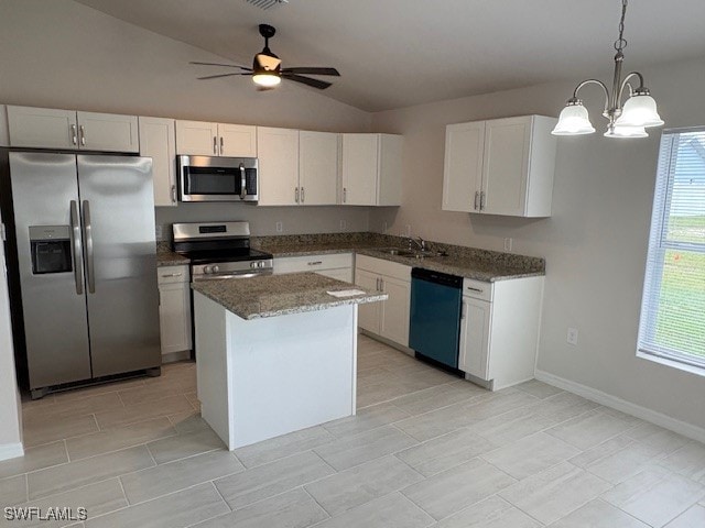 kitchen featuring lofted ceiling, white cabinets, hanging light fixtures, appliances with stainless steel finishes, and a kitchen island