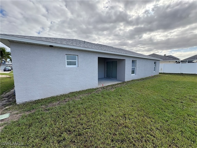 back of house with a yard and a patio