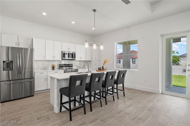 kitchen with appliances with stainless steel finishes, light hardwood / wood-style floors, and a healthy amount of sunlight