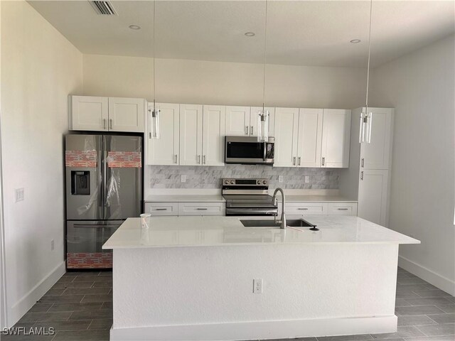 kitchen featuring appliances with stainless steel finishes, sink, decorative light fixtures, a center island with sink, and white cabinets