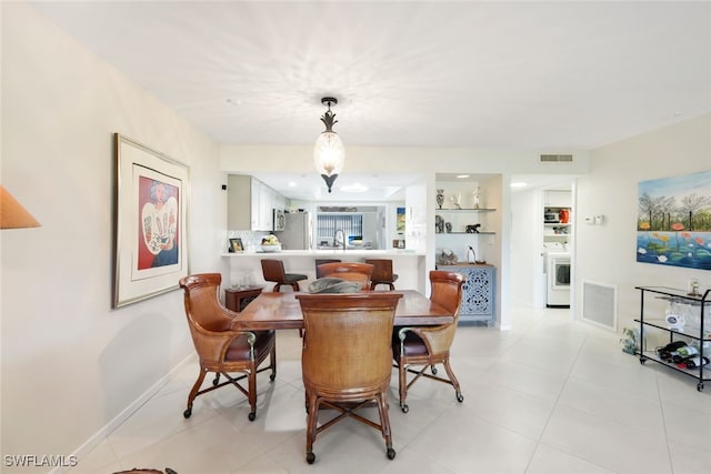 dining space featuring light tile patterned floors, baseboards, visible vents, and washer / clothes dryer